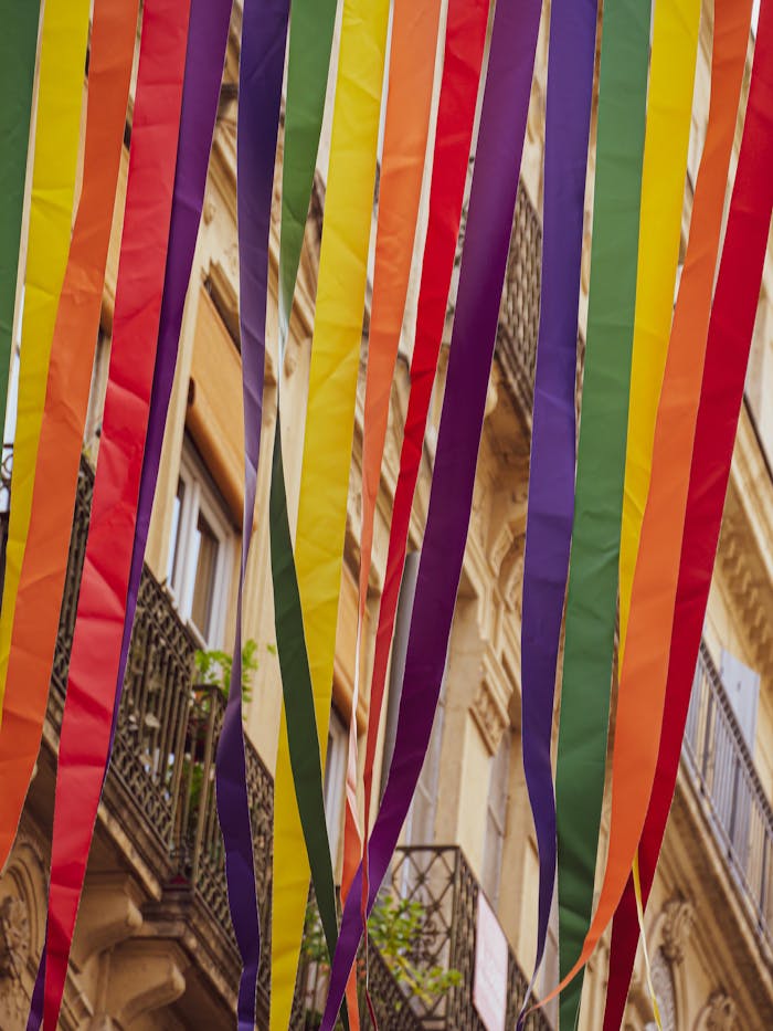 Vibrant multicolored ribbons adorn street with historic buildings in Montpellier, France.