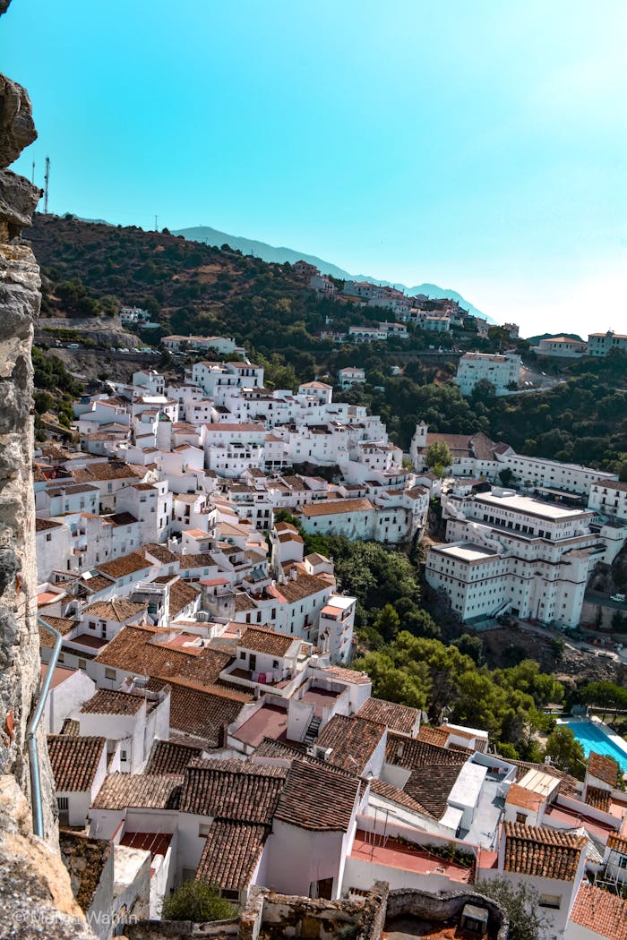Scenic view of a whitewashed village nestled in the hills of Spain, surrounded by lush greenery.