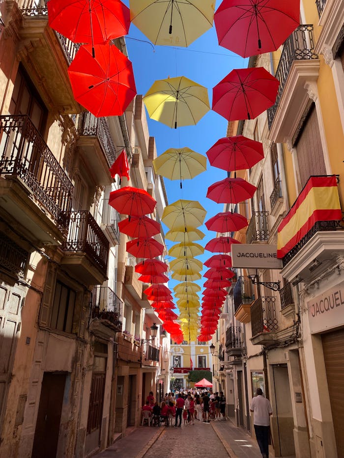 Street scene with vibrant red and yellow umbrellas hanging above, creating a festive atmosphere.