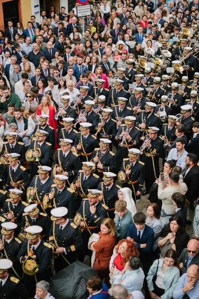 Aerial view of a vibrant Holy Week procession with a marching band in Seville, Spain.