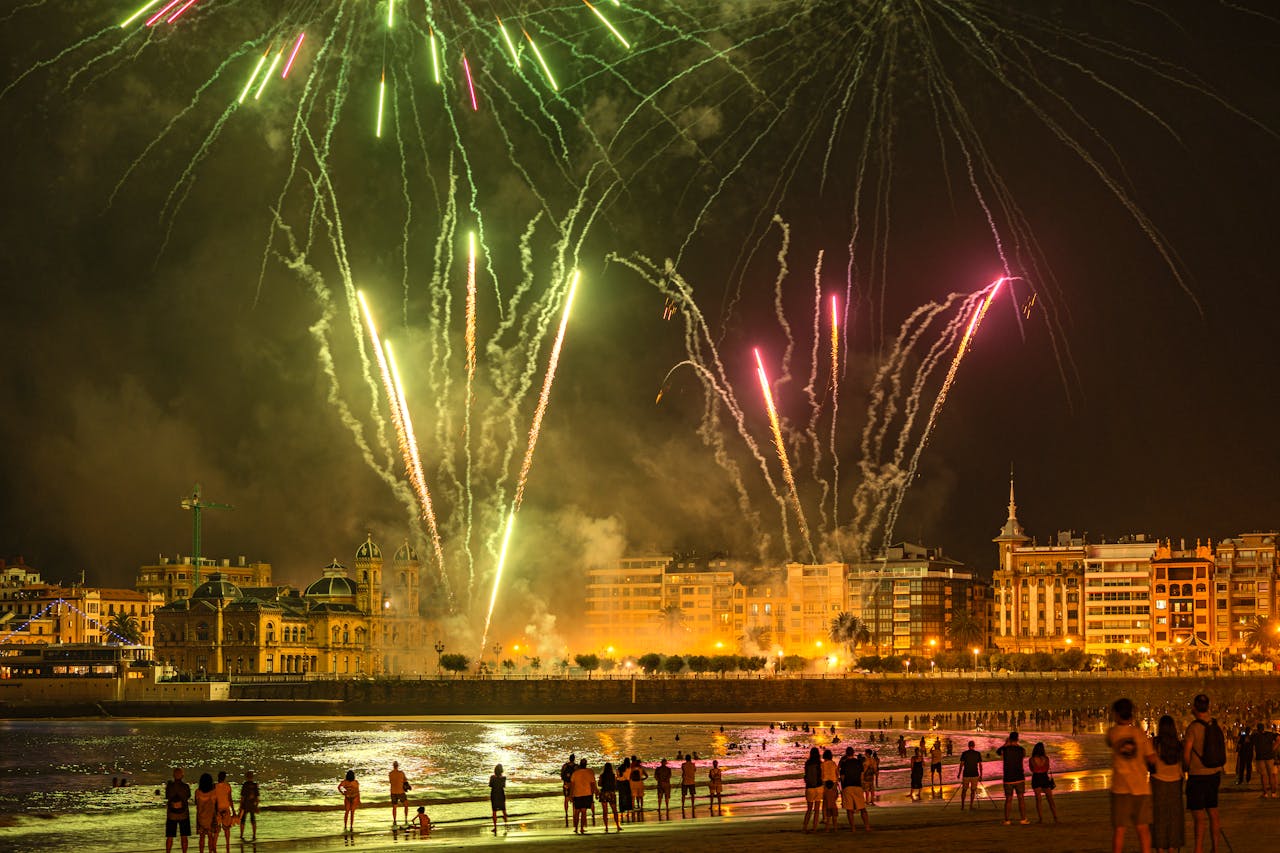 Fireworks illuminate the night sky over San Sebastián beach, creating a vibrant celebration atmosphere.